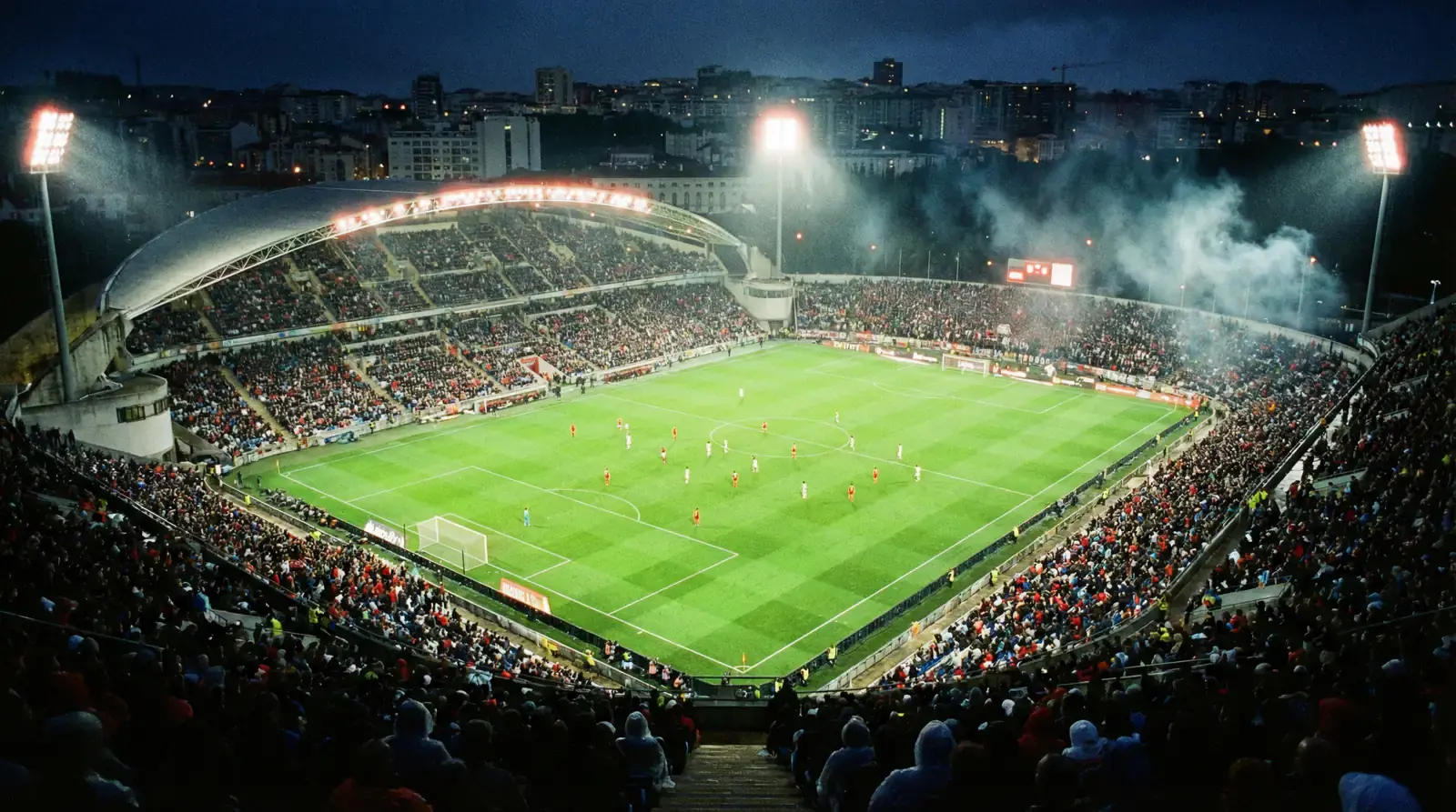 Vista de um relvado de futebol da I Liga portuguesa durante um jogo noturno com bancadas iluminadas